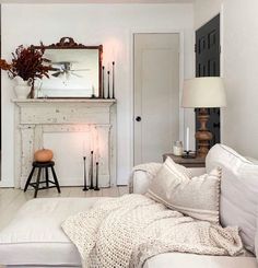 a living room filled with furniture and a fire place next to a white fireplace covered in candles