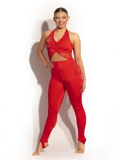 a woman standing in front of a white wall wearing red pants and a halter top