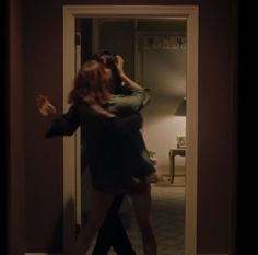 two women are hugging each other in front of an open door with the light on