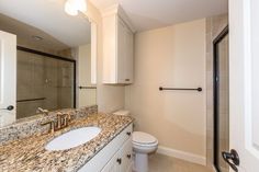 a bathroom with marble counter tops and white cabinets, along with a walk in shower