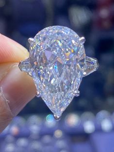 a close up of a person's hand holding a ring with a large diamond on it