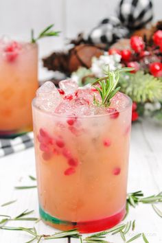 two glasses filled with drinks sitting on top of a white table next to christmas decorations