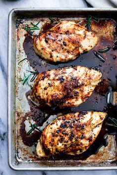 three pieces of chicken sitting on top of a pan covered in gravy and seasoning