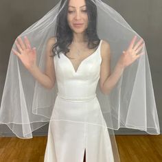 a woman wearing a white wedding dress with a veil on her head and hands in the air