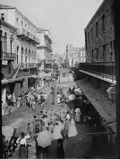 an old black and white photo of people walking down the street