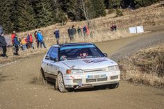 a car driving down a dirt road with people watching