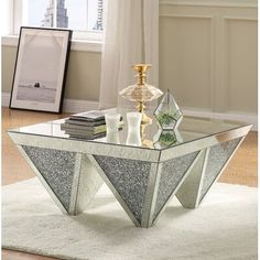 a glass coffee table with an unusual design on it's top, in front of a window