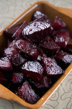 beets are in a brown bowl on a tablecloth covered table with a white and gray pattern