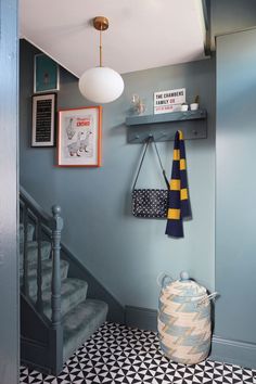 a hallway with blue walls, black and white flooring and an iron basket hanging on the wall