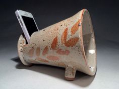 an orange and white ceramic speaker with a cell phone in it