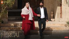 a man and woman holding hands in front of a building