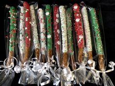 six christmas candles wrapped in clear cellophane and tied with ribbon on black background