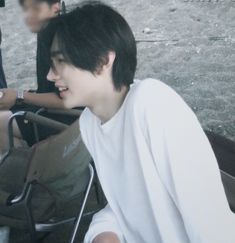 a young man sitting in the back of a pick up truck next to another person