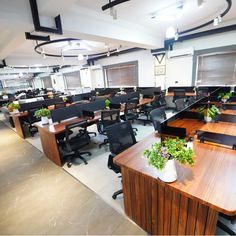 an empty office with desks and plants on the tables in front of them,