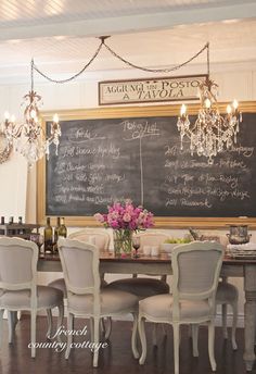 a dining room table with chairs and a chalkboard