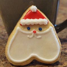 a cookie shaped like a santa clause on top of a counter next to a cup