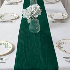 the table is set with white and green place settings