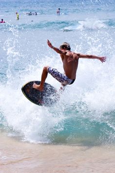 a man riding a surfboard on top of a wave in the ocean with people swimming in the water behind him