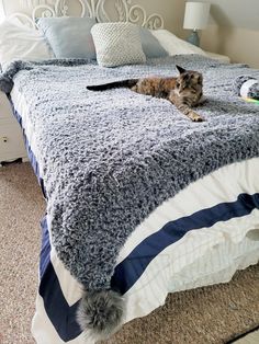 a cat laying on top of a bed covered in blankets and pillows next to a window