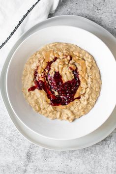 a white bowl filled with oatmeal and jelly sitting on top of a table