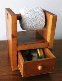 a wooden chair with yarn on top of it and two bottles in the bottom drawer