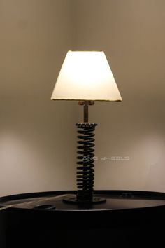 a lamp that is sitting on top of a round table in front of a white wall