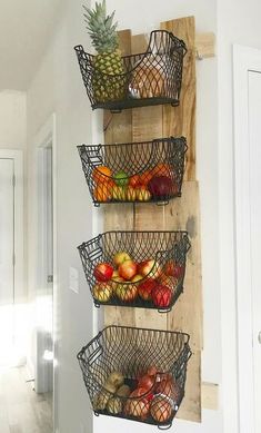 three metal baskets filled with fruit on top of a wooden wall hanging from the side of a door