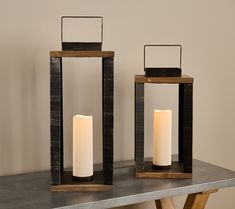 two wooden lanterns sitting on top of a table next to each other with candles in them