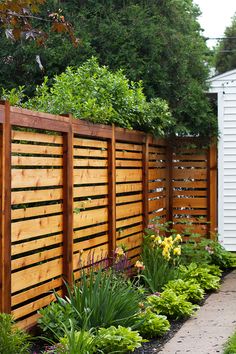 a wooden fence surrounded by plants and flowers