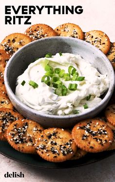 a plate full of crackers with cream cheese and chives in the middle on top