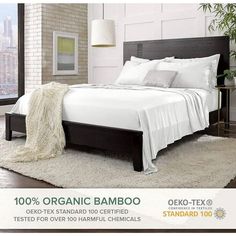 a bed with white sheets and pillows in a room next to a large window that reads 100 % organic bamboo