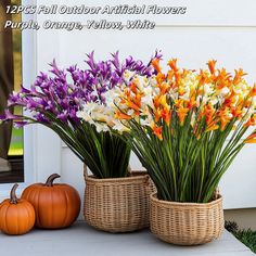 two baskets filled with flowers sitting on top of a white table next to pumpkins