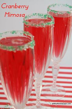 three wine glasses filled with cranberry mimosa on a red and white striped tablecloth