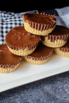 there are four chocolate cupcakes on the white plate and one is drizzled with chocolate