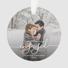 a round ornament with the words engaged and an image of a couple hugging