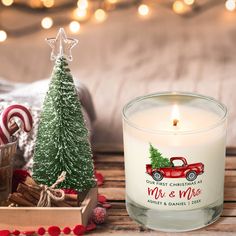 a glass candle next to a christmas tree on a wooden table with candy canes