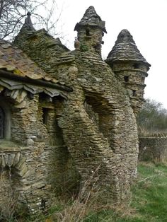 an old stone building with two towers and a door in the middle of it, surrounded by grass