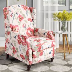 a living room with a flowered chair in the center and a vase on the side table