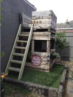 an outdoor play area made out of pallets and wooden crates with stairs leading up to the top