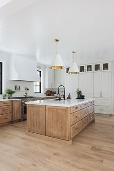 a large kitchen with wooden floors and white walls, along with an island in the middle