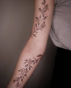 a woman's arm with flowers and leaves tattooed on the left side of her arm