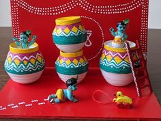 an assortment of colorful clay pots and figurines sitting on a red table top