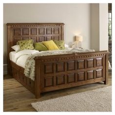 a large bed with wooden headboard and foot board sitting in a room next to a window