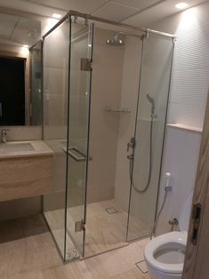 a bathroom with a toilet, sink and glass shower stall in the middle of it