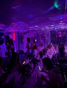 a group of people sitting around in a room with balloons and streamers on the walls