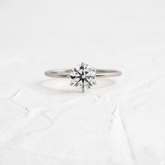 a white gold engagement ring with a single diamond in the center, on a white background