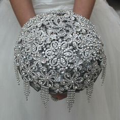 the bride is holding her wedding bouquet in one hand and wearing an elaborate brooch