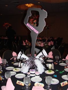 a black table topped with white plates and pink napkins next to a large sign