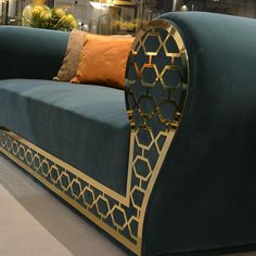 a blue couch with gold trim and pillows on it's back end in a store