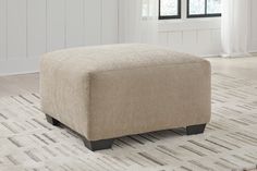 a beige ottoman sitting on top of a rug